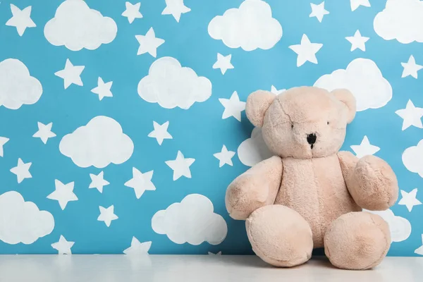 Teddy bear on white wooden table near wall with painted blue sky — Stock Photo, Image