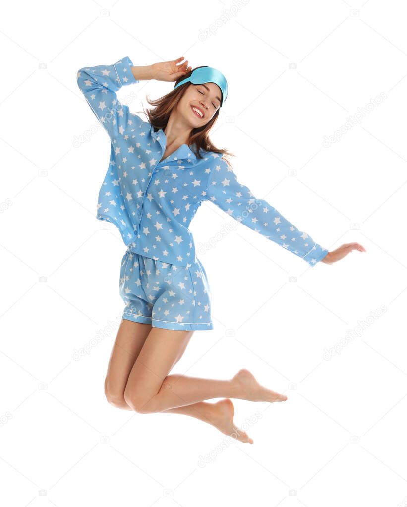 Beautiful woman with sleep mask jumping on white background. Bedtime