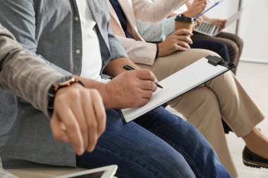 Dosyası olan bir adam iş görüşmesini bekliyor, yakın plan.