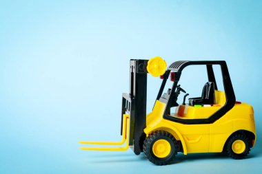 Mavi arka planda oyuncak forklift. Lojistik ve toptan satış kavramı