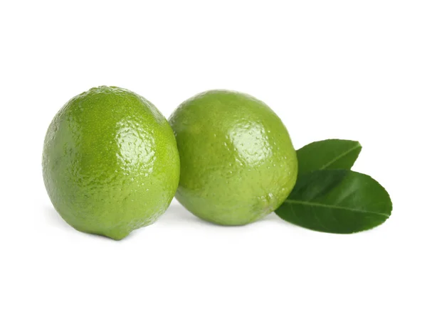 Limes freschi maturi con foglie verdi isolate su bianco — Foto Stock