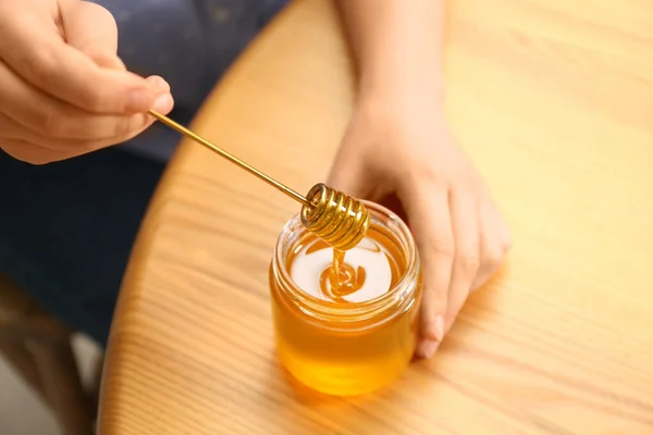 木製のテーブルで瓶の上に蜂蜜のディップを保持女性 クローズアップ — ストック写真