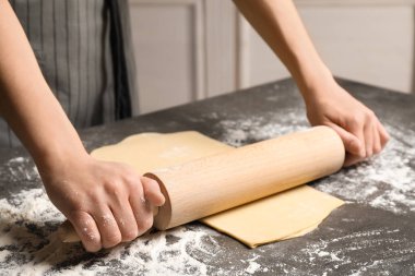 Gri masada hamuru yuvarlayan kadın, yakın plan.