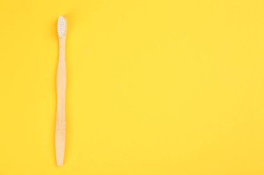 Sarı arka planda bambudan yapılmış diş fırçası, üst manzara. Metin için boşluk