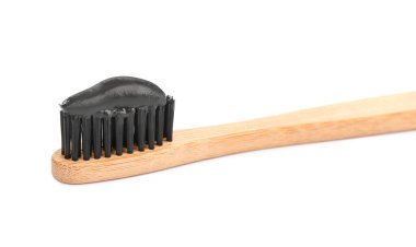 Beyaz üzerine izole edilmiş kömür macunu ile bambu diş fırçası