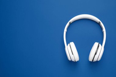 Parlak arkaplanda kulaklıklar, metin için yeri olan üst görünüm. 2020 yılının rengi (Klasik mavi)