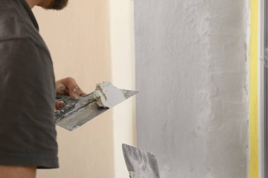 Pencere kenarına macun bıçağı ve sıva yapıştıran profesyonel bir işçi, yakın plan. İç onarım