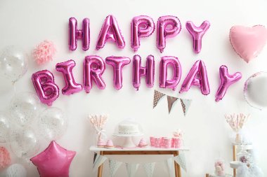 Beyaz duvardaki pembe balon harflerinden oluşan mutlu yıllar deyimi