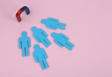Magnet attracting paper people on pink background, above view clipart