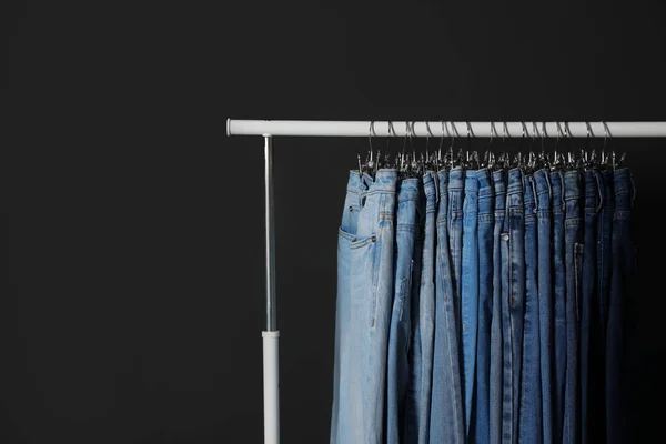 Bastidor con diferentes jeans sobre fondo gris oscuro —  Fotos de Stock