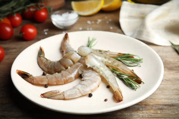 Fresh raw shrimps with rosemary and pepper on wooden table — Stock Photo, Image