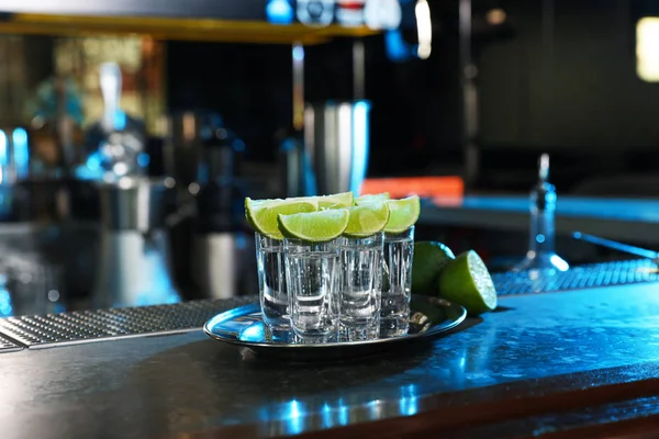 Mexican Tequila shots with lime slices on bar counter