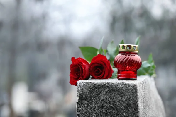 Czerwone róże i świeca na szarym granitowym nagrobku na zewnątrz. Pogrzeb — Zdjęcie stockowe