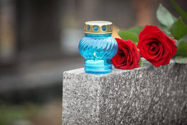 Červené růže a svíčky na šedém žulovém náhrobku venku. Pohřeb — Stock fotografie