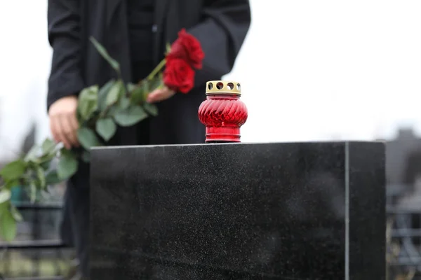 Frau mit roten Rosen im Freien, Fokus auf Kerze. Trauerfeier — Stockfoto