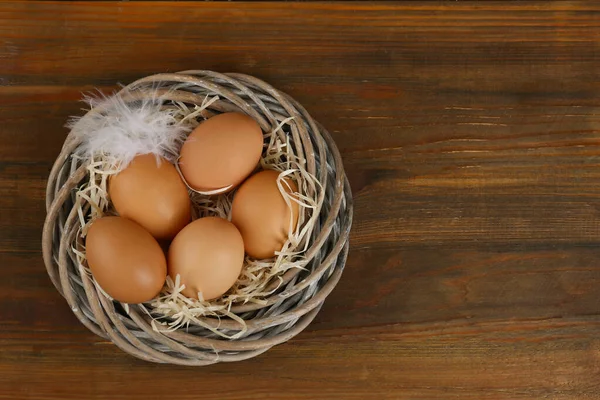 Huevos Gallina Crudos Plumas Nido Mimbre Sobre Mesa Madera Vista — Foto de Stock