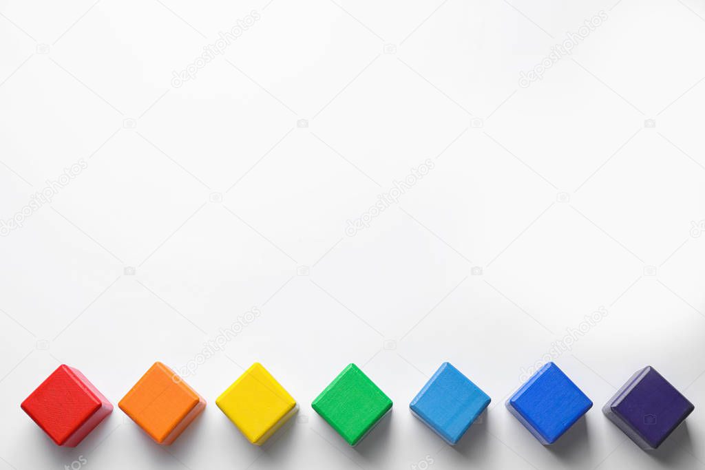 Bright wooden cubes on white background, top view. Rainbow colors