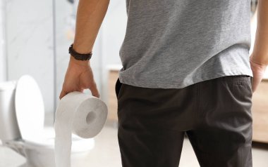 Tuvaletteki klozetin yanında kağıt rulo yapan adam, yakın plan.