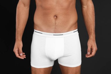 İç çamaşırlı adam siyah arka planda, yakın plan.