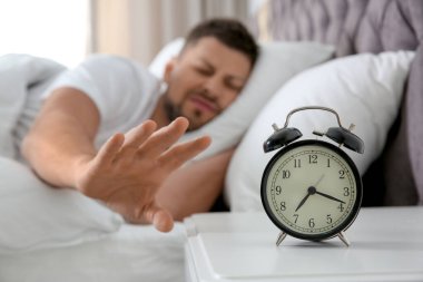 Uykulu adam sabahları evdeki çalar saati kapatıyor. 