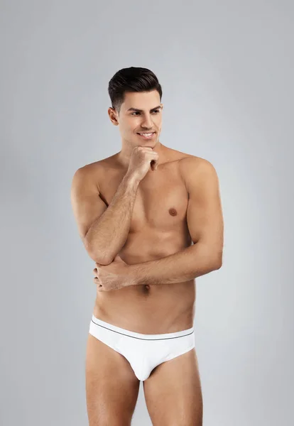Schöner Mann in weißer Unterwäsche auf hellgrauem Hintergrund — Stockfoto