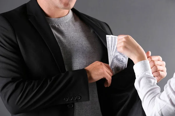 Vrouw geven steekpenningen geld naar man op donkere achtergrond, close-up — Stockfoto