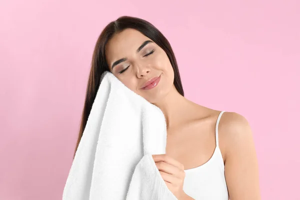 Młoda kobieta wycierająca twarz ręcznikiem na jasnoróżowym tle — Zdjęcie stockowe
