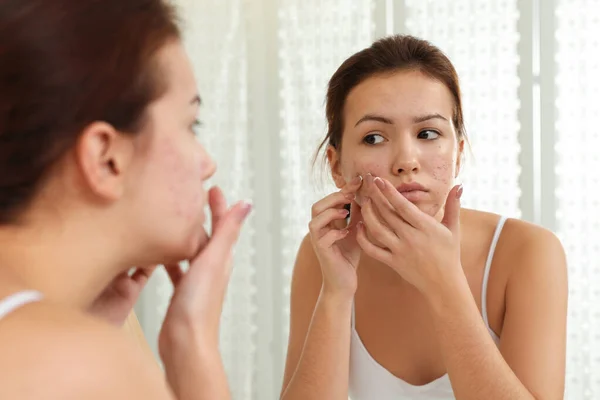 Teen girl with acne problem squeezing pimple near mirror in bath — Stock Photo, Image