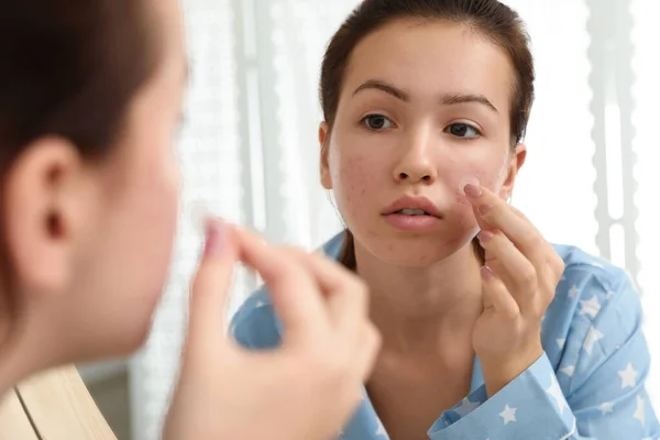 Teen girl applying acne healing patch near mirror in bathroom — Stock Photo, Image