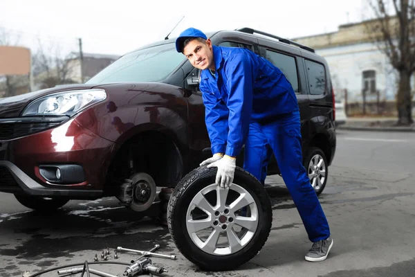Trabalhador mudando roda de carro no serviço de pneus — Fotografia de Stock