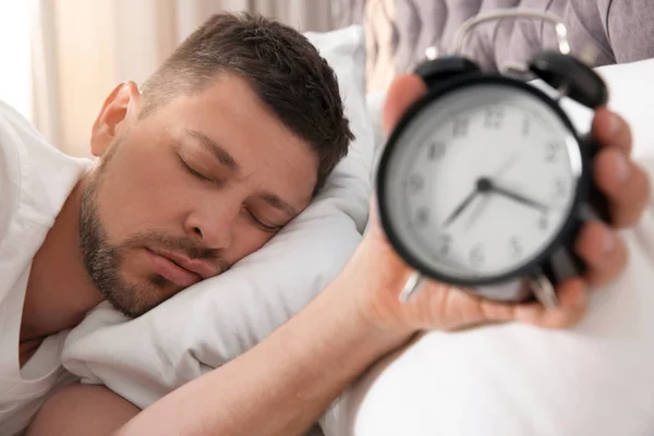 Man with alarm clock sleeping at home in morning — Stock Photo, Image