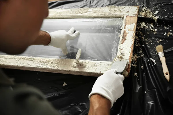 Man reparerar gamla skadade fönster vid bordet inomhus, närbild — Stockfoto