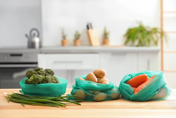 Mutfaktaki ahşap masada sebzeli ağ torbaları. — Stok fotoğraf