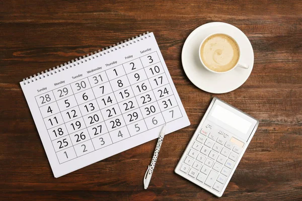 Flache Liegekomposition mit Kalender und Tasse Kaffee auf Holz-T — Stockfoto