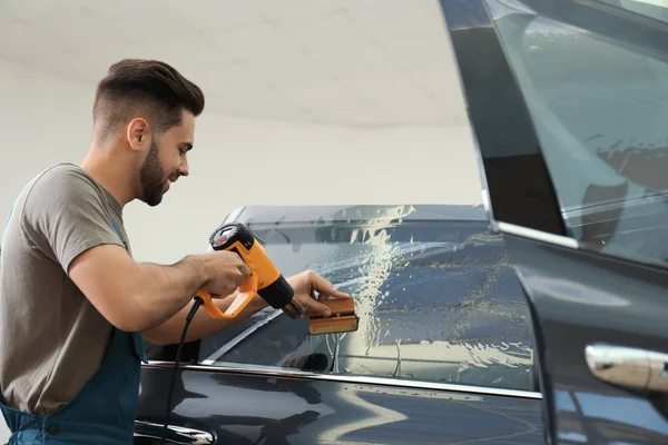 Trabalhador matizando janela do carro com arma de calor na oficina — Fotografia de Stock