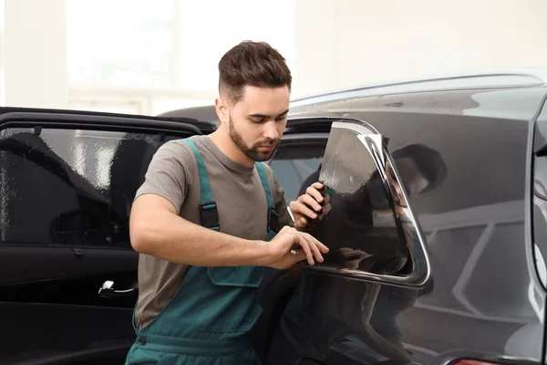 Obrero teñido ventana del coche con papel de aluminio en el taller — Foto de Stock