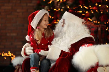 Santa Claus and little girl near Christmas tree indoors