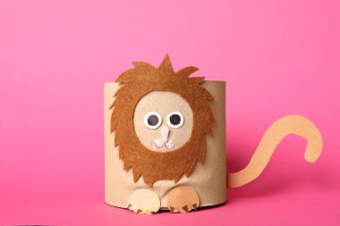 Pembe arka planda tuvalet kağıdı rulosundan yapılmış oyuncak aslan.