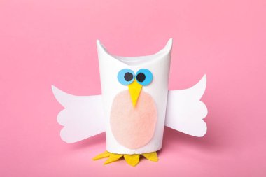 Pembe arka planda tuvalet kağıdı merkezinden yapılmış oyuncak baykuş.