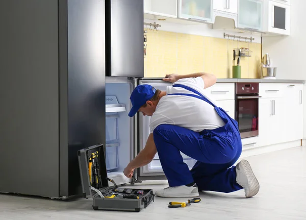 Técnico masculino reparando refrigerador quebrado na cozinha — Fotografia de Stock