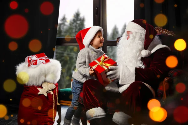 Santa Claus giving Christmas gift to little boy near window indo — Stock Photo, Image