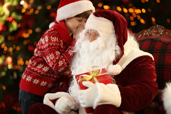 Santa Claus y el niño pequeño cerca del árbol de Navidad en el interior —  Fotos de Stock