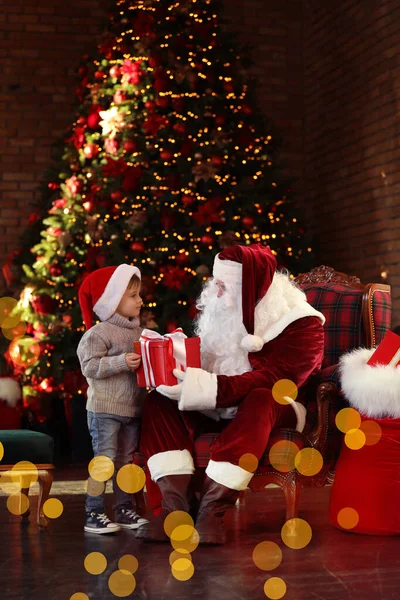 Papá Noel regalando a un niño pequeño cerca del árbol de Navidad ind — Foto de Stock