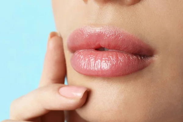 Woman with beautiful full lips on light blue background, closeup — Stock Photo, Image