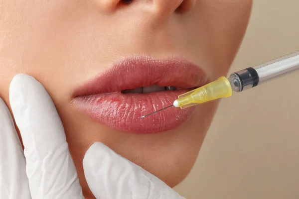 Woman getting lip injection on beige background, closeup — Stock Photo, Image