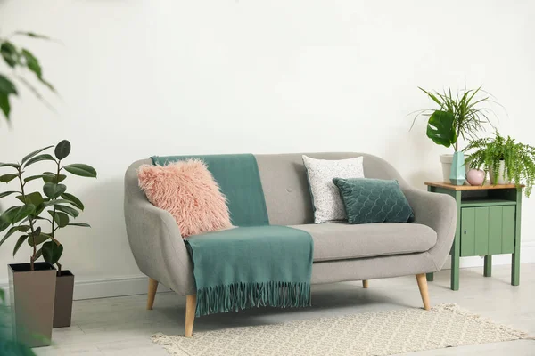 Oreillers doux et plaid sur canapé gris dans le salon — Photo