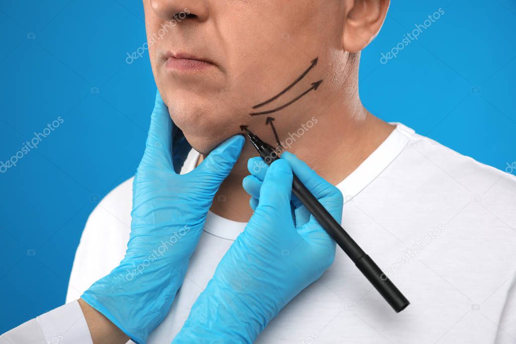 Surgeon with marker preparing man for operation on blue backgrou