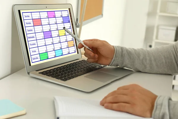 オフィスのノートパソコンでカレンダーアプリを使用している若者 クローズアップ — ストック写真