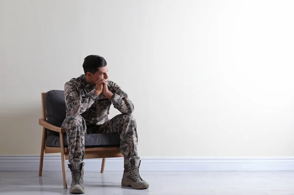 Oficial militar estressado sentado em poltrona perto da parede branca em — Fotografia de Stock