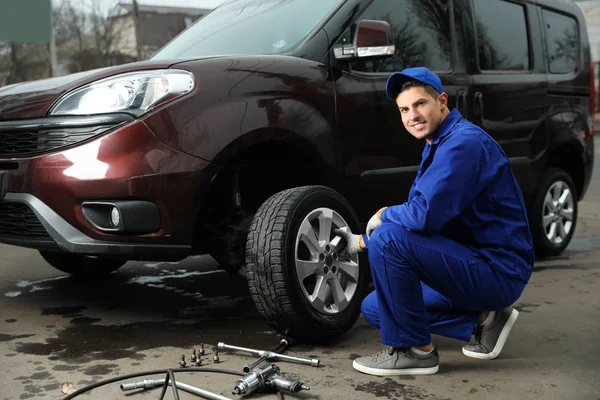 Trabalhador mudando roda de carro no serviço de pneus — Fotografia de Stock